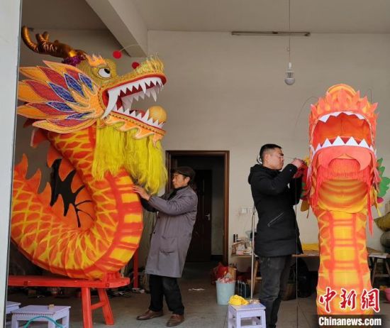 1月28日，中国民间文艺家协会会员、灯彩师傅汪宣烈(左一)在家中忙碌赶制板龙灯。(受访者供图)